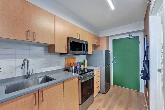 Modern kitchen with sleek cabinetry, stainless steel appliances, and contemporary design featuring a vibrant green door.
