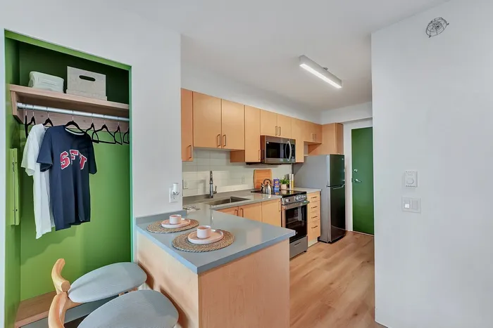 Chic apartment kitchen with sleek wooden cabinets, modern appliances, and inviting breakfast bar seating.