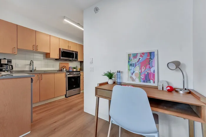 Contemporary kitchen with sleek wooden cabinets, modern appliances, and a cozy workspace with vibrant wall art.