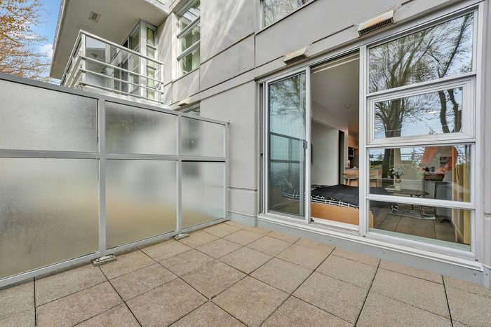 Bright and inviting apartment patio with modern sliding doors leading to a cozy interior, surrounded by lush greenery and natural light.