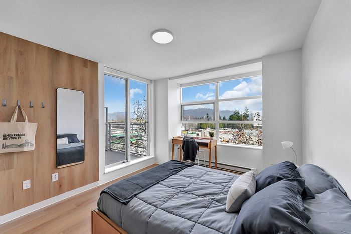 Bright and airy bedroom with modern decor, expansive windows offering stunning city views, and a cozy study corner.