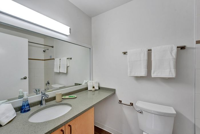 Modern bathroom with sleek countertop, large mirror, and pristine white towels, offering a clean and elegant design.