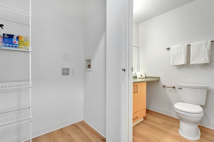 Sleek bathroom with hardwood flooring, modern fixtures, and ample storage space.