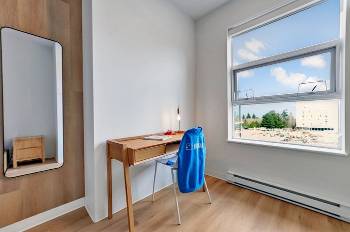 Bright home office with a sleek wooden desk and large window offering abundant natural light and scenic views.