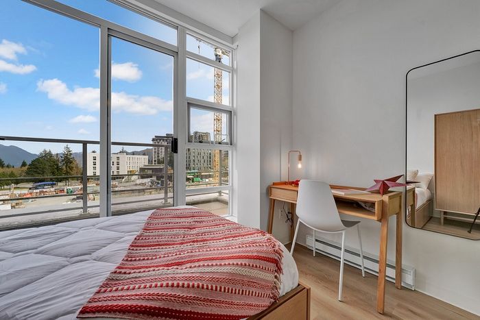 Modern bedroom with large windows showcasing scenic views, natural light illuminating a cozy workspace with minimalist décor.