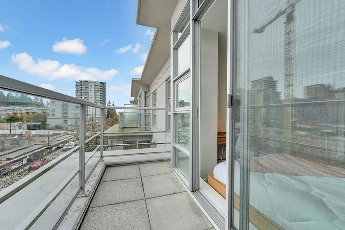 Modern apartment balcony with city views, featuring sleek glass railings and seamless indoor-outdoor living.