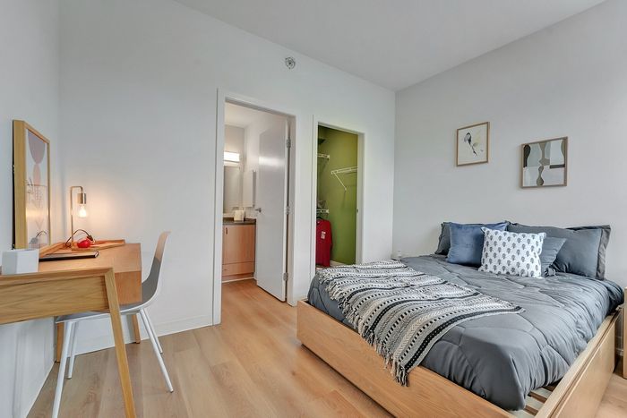 Cozy bedroom with modern decor featuring a comfortable bed, stylish desk, and natural light for a serene atmosphere.
