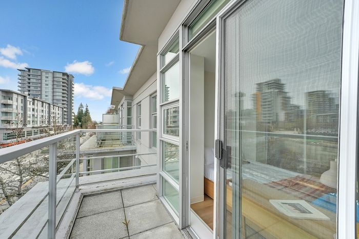 Bright urban balcony with contemporary glass railing, offering sweeping views of modern high-rise buildings and blue skies.