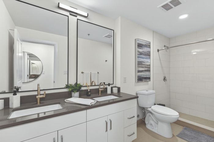 Modern bathroom featuring sleek double vanity, stylish black framed mirrors, and elegant fixtures with contemporary art.