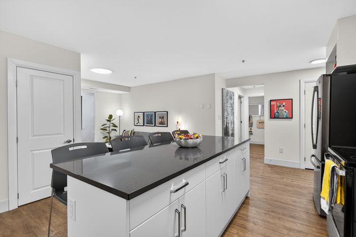 Modern kitchen with sleek black countertops, contemporary decor, and artwork on the walls offering a stylish and inviting ambience.