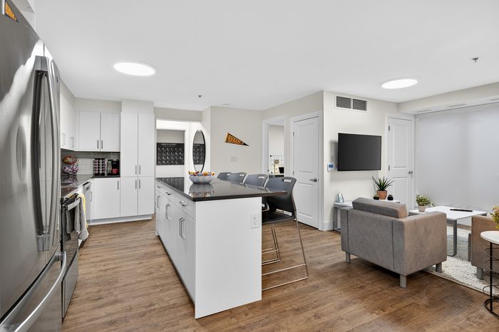 Modern open-concept kitchen and living area with sleek white cabinetry, a stylish breakfast bar, and cozy lounge space.