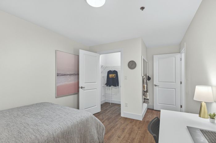 Modern bedroom with sleek decor, featuring a walk-in closet, minimalist desk, and soft lighting on hardwood floors.