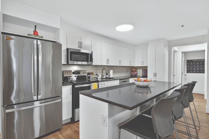 Modern kitchen with sleek stainless steel appliances, stylish white cabinetry, and a spacious island with bar seating, perfect for entertaining.