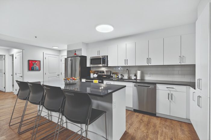 Modern kitchen with sleek white cabinetry, stainless steel appliances, and a chic island with bar seating, perfect for entertaining.