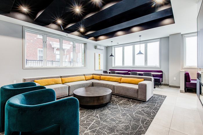 Elegant lounge area with modern gray and yellow sectional sofa, vibrant turquoise chairs, and stylish lighting, ideal for social gatherings.