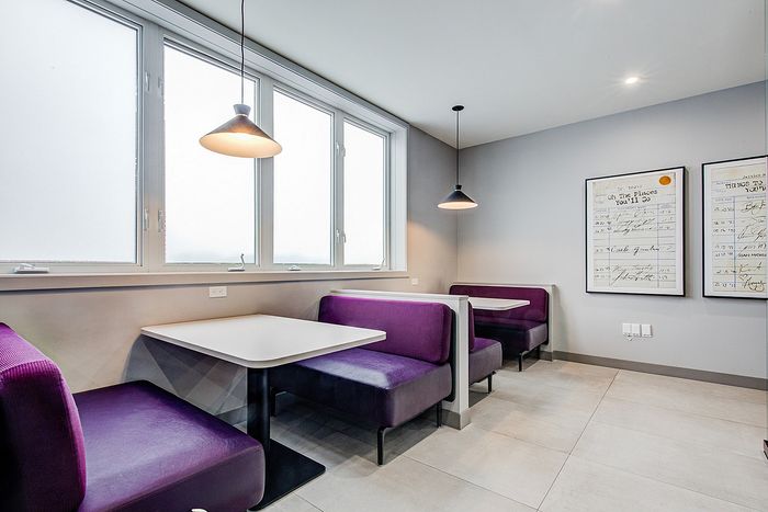 Chic dining corner with modern purple booths and minimalist pendant lighting, perfect for cozy meals and casual gatherings.