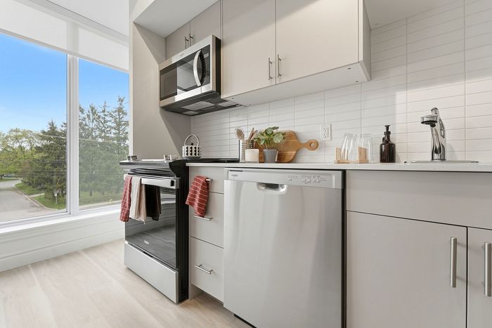 Bright modern kitchen featuring sleek stainless steel appliances, large windows with a scenic view, and elegant cabinetry.