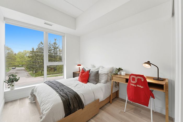 Bright and inviting bedroom with a large window overlooking lush greenery, featuring a cozy bed, modern desk, and stylish decor.