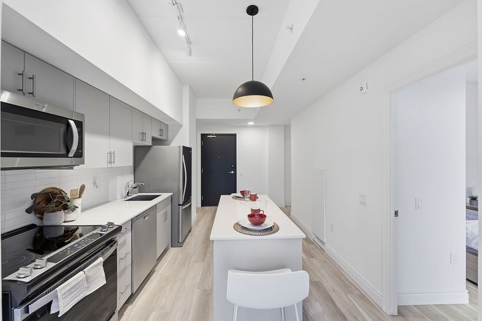 Modern kitchen with sleek gray cabinets, stainless steel appliances, and elegant pendant lighting above a chic breakfast island.