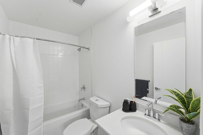 Modern bathroom featuring a sleek white vanity with mirror, chic bathtub, and minimalist decor.