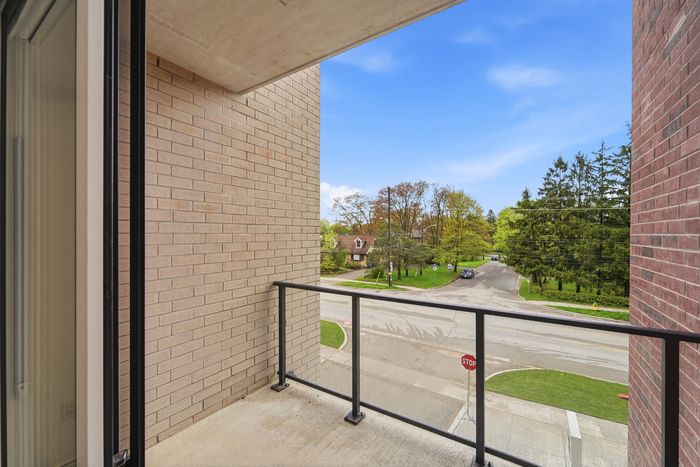 Inviting apartment balcony with stylish brick walls offering a picturesque suburban view, perfect for relaxation and enjoying the serene neighborhood.
