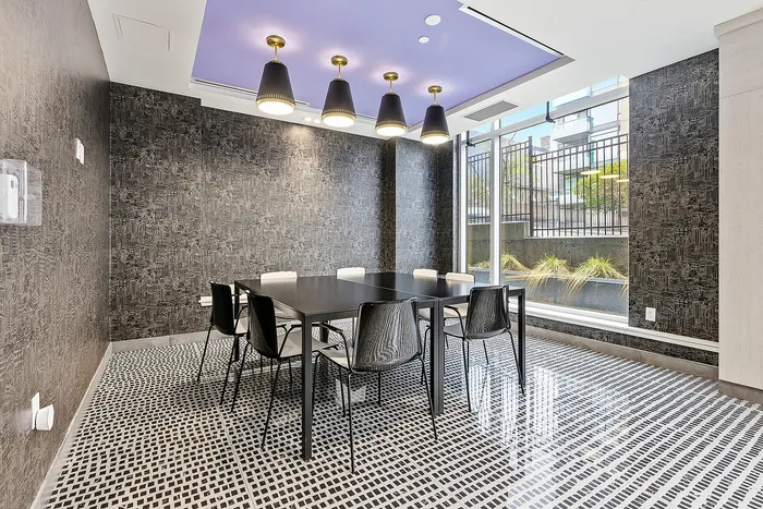 Elegant dining room with a modern table, sleek black chairs, and stylish overhead lighting, featuring floor-to-ceiling windows for natural light.