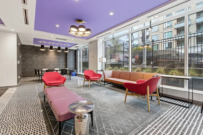 Modern lounge area with bold purple ceiling, chic lighting, plush seating, and floor-to-ceiling windows offering city views.