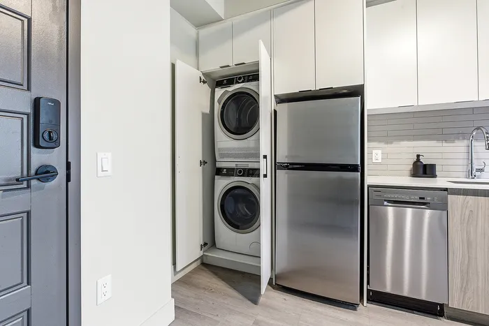 Contemporary apartment kitchen featuring stainless steel appliances and an in-unit washer and dryer for modern living.