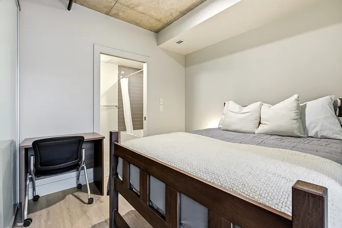 Cozy bedroom with a stylish wooden bed, plush bedding, and a compact desk perfect for work or study.