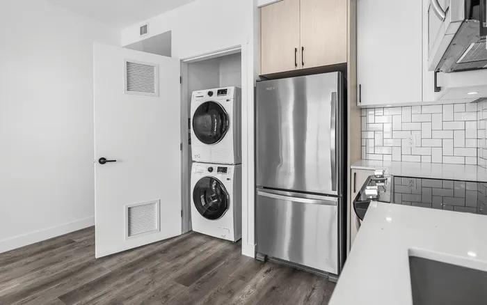 Modern kitchen with sleek stainless steel appliances, stylish tile backsplash, and convenient in-unit washer and dryer.
