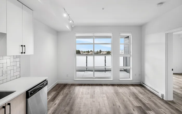 Bright and modern apartment interior featuring sleek wooden flooring, large windows offering ample natural light, and a contemporary kitchen with stylish cabinetry.