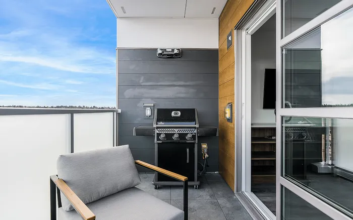 Chic apartment balcony featuring a modern grill and cozy seating, perfect for outdoor relaxation and entertaining with a stunning view.