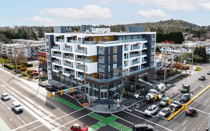 Modern multi-story residential building with sleek balconies, set at a vibrant city intersection offering scenic views and urban convenience.