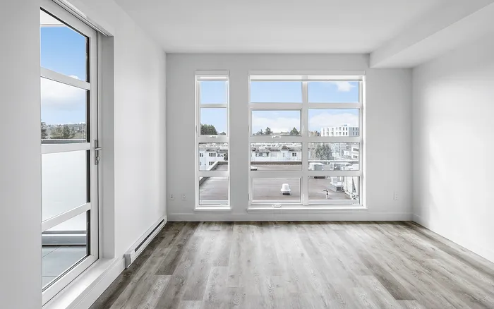 Bright apartment interior featuring large windows with stunning city views and elegant wood flooring.