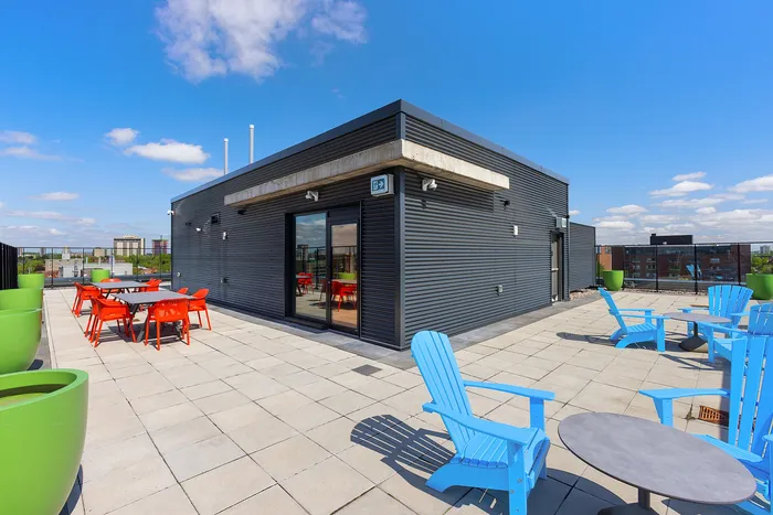 Inviting rooftop patio with vibrant orange seating and modern design, offering stunning city views and a perfect spot for relaxation.