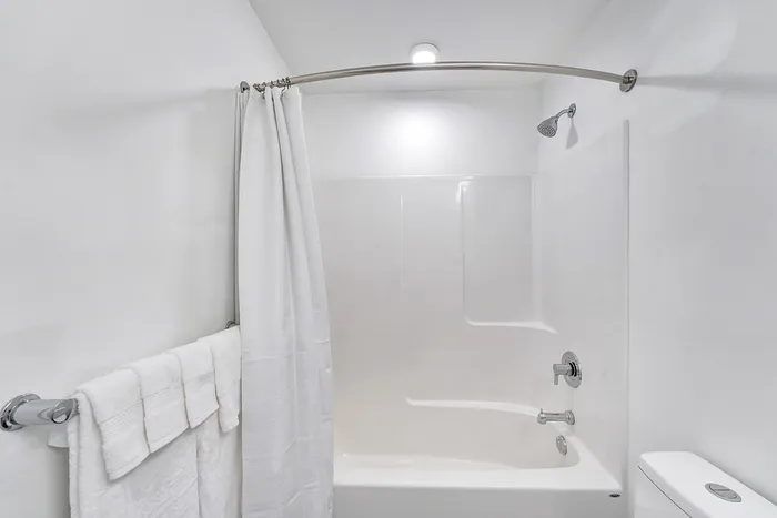 Bright, modern bathroom with a sleek white bathtub and elegant curved shower curtain rod.