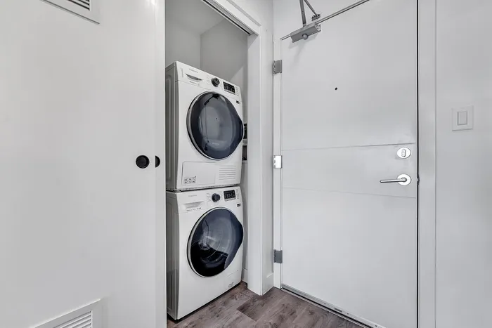 Modern apartment entryway featuring a sleek stacked washer and dryer unit, accentuating convenience and style.