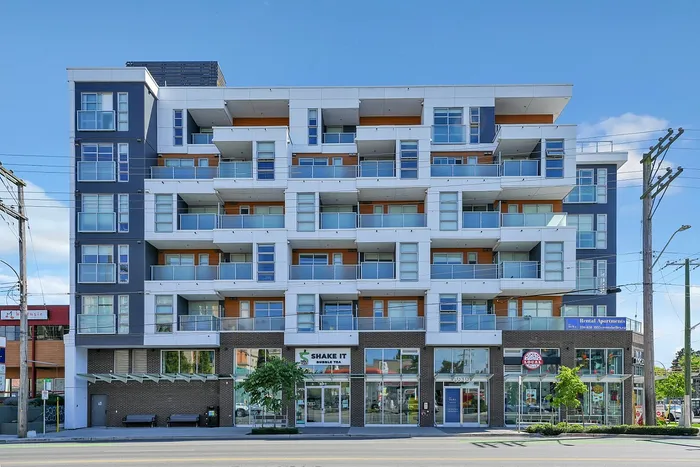Modern multi-story apartment building with sleek balconies and ground-floor retail, offering urban living convenience.