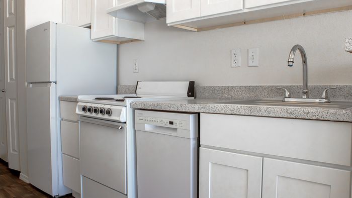 Metro Flats kitchen with white appliances, cabinetry, and counter space