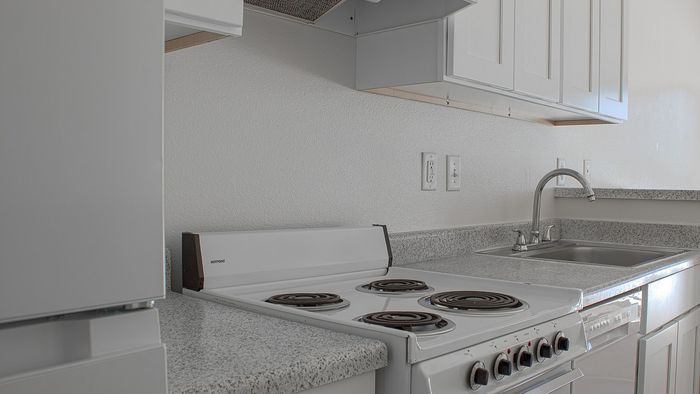 Studio apartment kitchen with electric range, dishwasher, and countertops