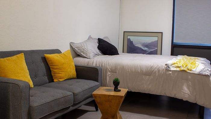 Furnished Tate studio apartment at The Oslo in Murray, Utah featuring a bed, couch, and open living space