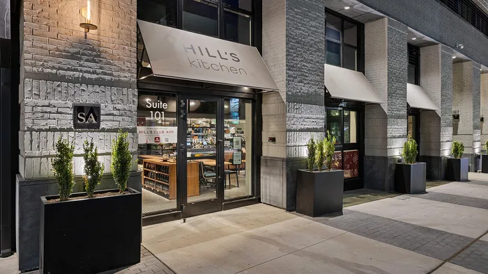 Hill’s Kitchen exterior at night viewed through Sugar Alley windows