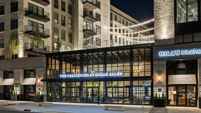 The front-facing exterior of Sugar Alley is striking in the evening, with clean modern lines and a warm glow from its interior lights. This signature Sugar House address makes a bold statement day or night, reflecting contemporary elegance from every angle.