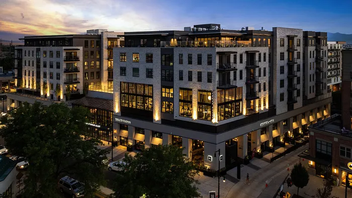 Corner view of Sugar Alley Apartments with retail storefronts and sunset lighting