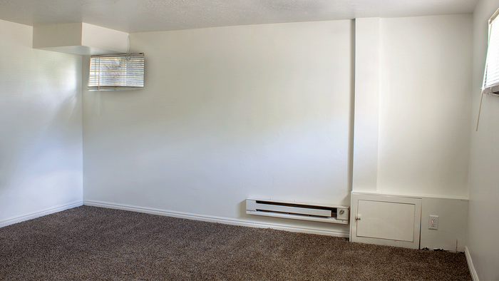 Carpeted basement bedroom with natural light and wall heating in the 5-bedroom Stone Creek Village home.