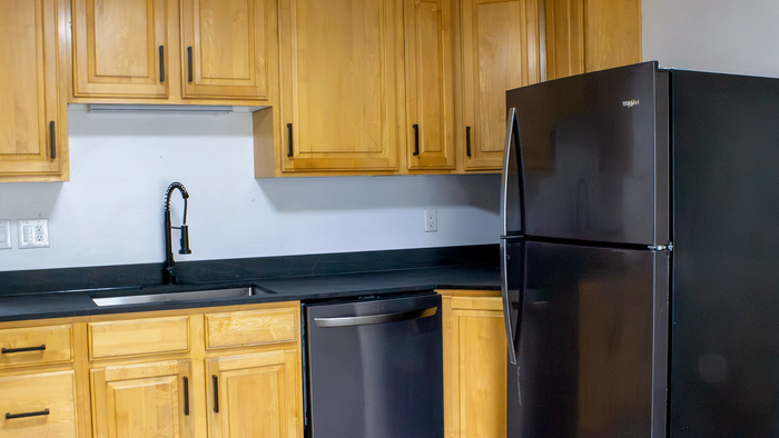 Remodeled kitchen in Stone Creek Village 5-bedroom Bountiful house with wood cabinets, black refrigerator, and dishwasher.