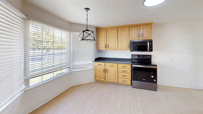 Bright kitchen nook with bay windows, wood cabinetry, and stainless steel appliances in the Stone Creek Village home.