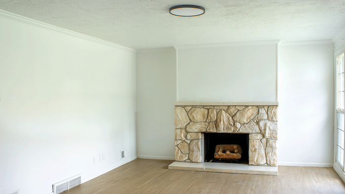 Living room with stone fireplace and wood-style floors in the 5-bedroom Stone Creek Village house.