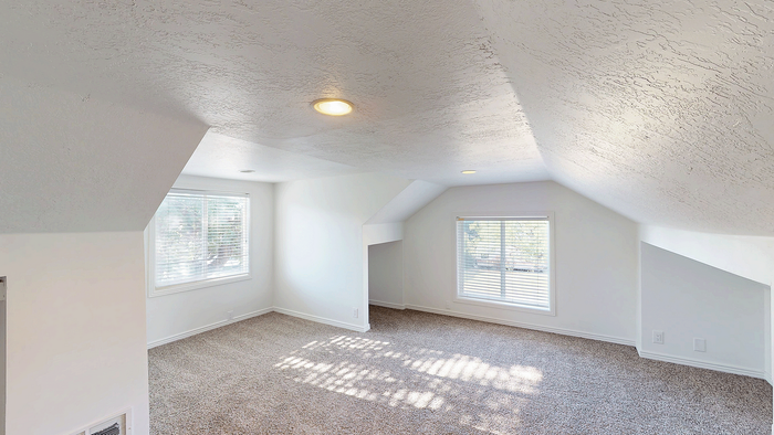 Loft area with carpet flooring and large windows in the 5-bedroom Stone Creek Village stand-alone house.