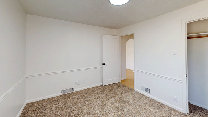 Main floor bedroom with carpet flooring, closet, and neutral finishes in the Stone Creek Village 5-bedroom home.